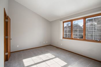 An empty bedroom with large windows and carpeting